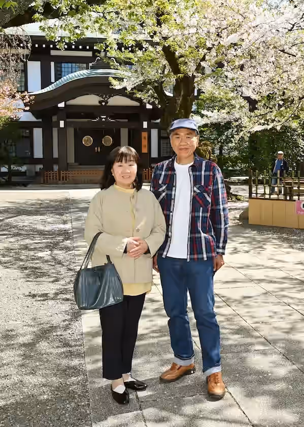 春の拝殿を背景に - 温かな春日に笑顔のご夫婦