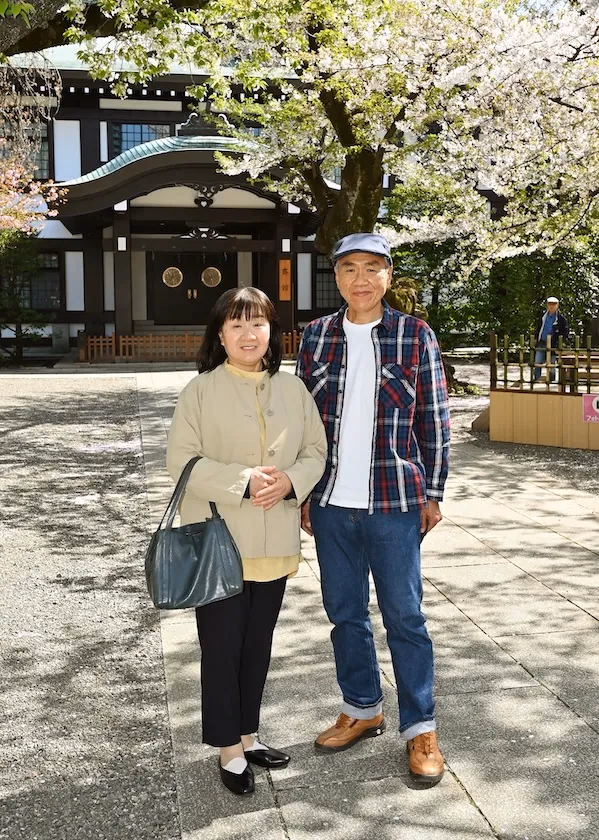 春の拝殿を背景に - 温かな春日に笑顔のご夫婦